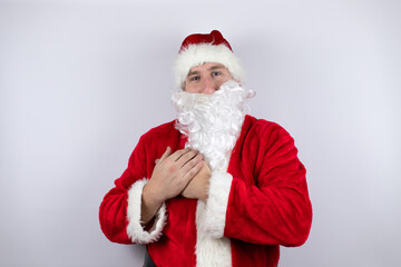 Fototapeta na wymiar Man dressed as Santa Claus standing over isolated white background smiling with her hands on her chest and grateful gesture on her face.