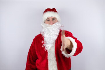 Man dressed as Santa Claus standing over isolated white background smiling friendly offering handshake as greeting and welcoming