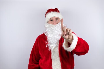 Man dressed as Santa Claus standing over isolated white background showing and pointing up with fingers number one while is serious