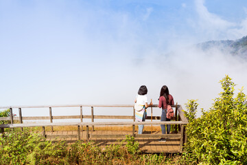 asian woman traveler see sunrise from top of mountain in spring season