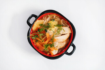 Tom yam in a plate with handles. Asian soup with noodles, carrots and chicken.