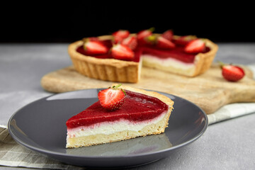 Piece of strawberry pie with fresh berries topping on grey plate on grey stone background