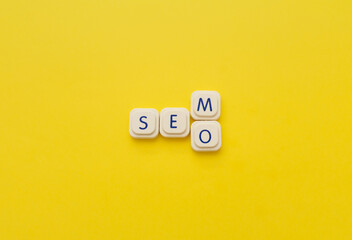 SEM or SEO words made with letters of a board game, over a yellow background. Search engine concepts