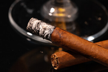Burning cigar against black background close up © fotofabrika