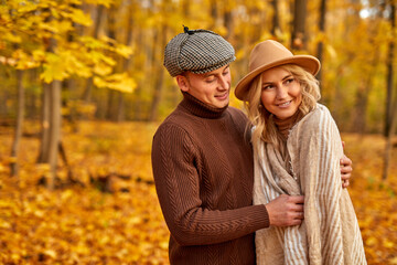 Fototapeta premium married couple in autumn-style clothes walk outdoors in autumn forest, two lovers posing together, carefree