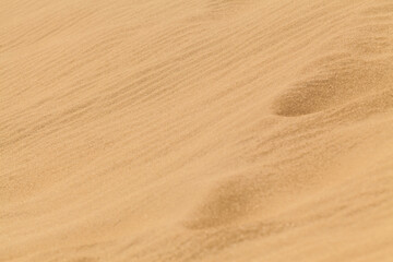 Yellow desert sand with footprints on it.
