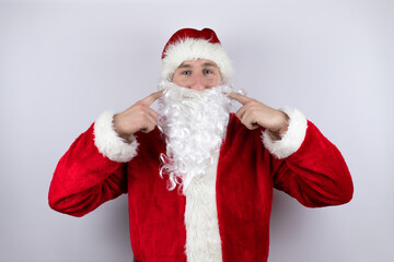 Fototapeta na wymiar Man dressed as Santa Claus standing over isolated white background smiling confident showing and pointing with fingers teeth and mouth