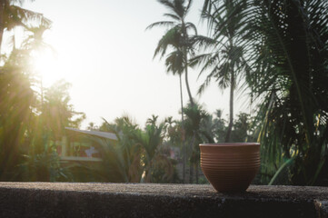 Coffee cup (Bhar) in sunset sunlight. Summer fresh cool look. Muddy mud tea cup made of clay for hot drink on roof beam of a residential building with bokeh city in the background.