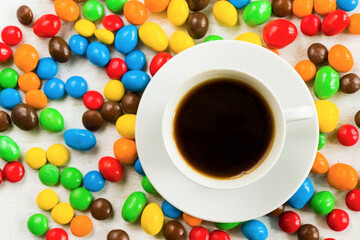 Fototapeta na wymiar Cup of black coffee and chocolate candy on the white background, colorful candy, close-up and macro