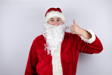 Man dressed as Santa Claus standing over isolated white background smiling and doing the ok signal with her thumbs