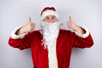 Fototapeta na wymiar Man dressed as Santa Claus standing over isolated white background smiling and doing the ok signal with her thumbs