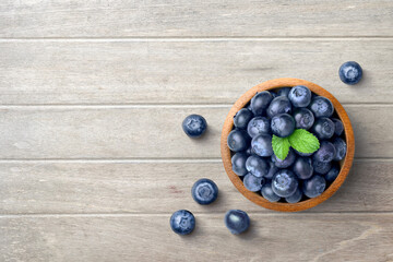 Flat lay (top view) of Blueberries in wooden bowl on wooden table background.