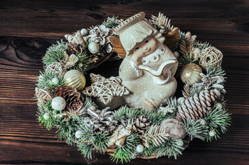 Christmas wreath, figurine of an angel in the center on a wooden background. Christmas composition.