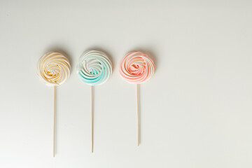 meringue or beze cookies with a wooden stick on the white background - obrazy, fototapety, plakaty