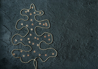 Gold decoration in the form of a Christmas tree on a black background.Place for signature.