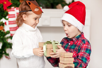 Obraz na płótnie Canvas Boy and girl brother and sister give each other christmas gifts