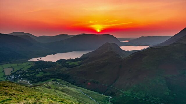 Sunset in Lake District.Sun setting over mountain lake.Orange evening sky over hills.4K nature time lapse video clip.Tranquil landscape scenery.
