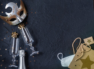 Carnival mask, wine glasses, bottle of champagne, gift bag, protective medical mask on a black background. Place for signature.