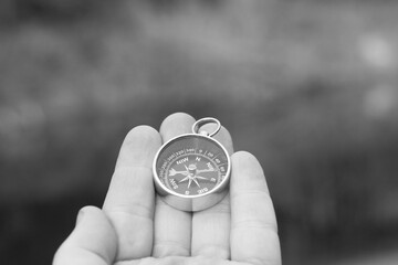 Classic navigation compass in hand on smoke background as symbol of tourism with compass, travel...
