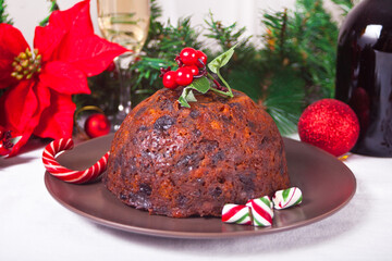 Traditional Christmas pudding with holly on top and Christmas decoration on the background