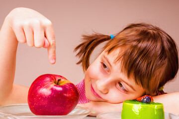 Beautiful young child girl having hard choice between healthy and unhealthy food. Health, diet, lifestyle concept.