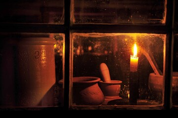 Lit candle in window of old log building