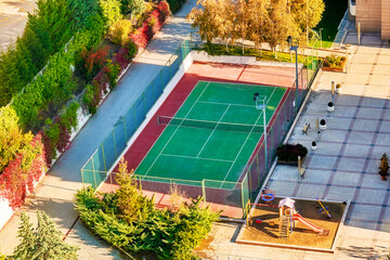 Clay or hard surface outdoor tennis court and a playground.