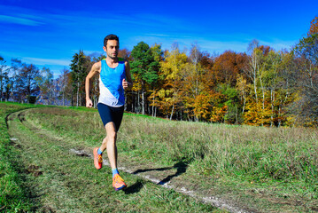 Running athlete during a workout among hillside meadows and woods