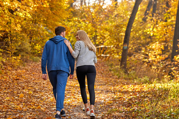 Obraz premium rear view on couple enjoying jogging on a country road through the beautiful autumn forest, exercise and fitness concept