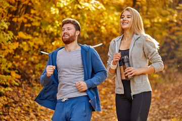 joyful positive couple running in wooded forest area, autumn nature. man and woman training, exercising. fitness healthy lifestyle concept