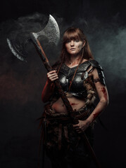 Armed with two handed axe nordic grimy amazon in dark armour with brown hairs poses in dark...