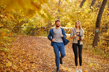 man and woman jogging in the forest. cheerful friends running in the autumn park, enjoy leading healthy lifestyle. the integrity and refreshing