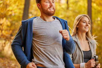 man and woman jogging in the forest. cheerful friends running in the autumn park, enjoy leading healthy lifestyle. the integrity and refreshing