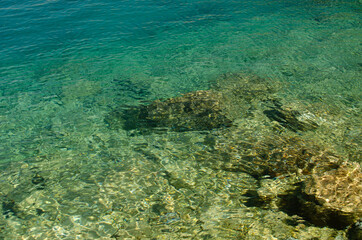 Fototapeta na wymiar The rocky background of the sea throught emerald water