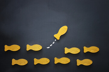 different fish swimming opposite way of identical ones. Courage and success concept. Blackboard...