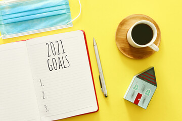 Business concept of top view 2021 goals list with notebook, cup of coffee over wooden desk