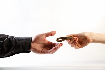 Fototapeta premium A man's hand in a black shirt takes a wad of folded money from a woman's hand. Side view. White background. The concept of the world anti-corruption day, 9 December