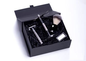 Razor and brush on stand, perfume, balsam and blades in black box on a white background.