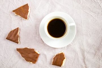 Cup of black espresso coffee and chocolate bars on the white cloth background