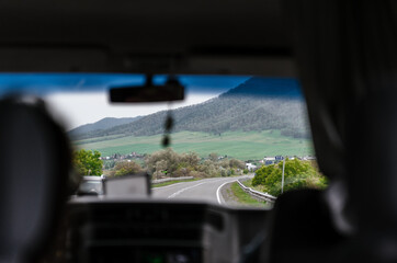 People go on vacation. Car trip to the mountains. Passenger POV at summer day on a country road, having fun driving the empty highway on tour journey.