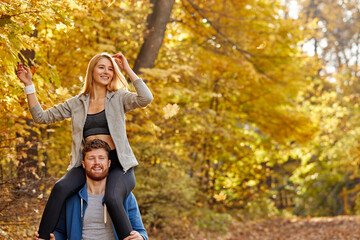 positive joyful couple spend time in the autumn park during fall, yellow trees in the background. in the nature - Powered by Adobe