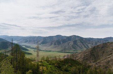 Photo of a Mountain summer Landscape. Travel location of popular tourist attraction. View of beautiful nature. Grassy field, hills, power lines on cloudy sky background.
