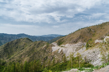 Photo of a Mountain summer Landscape. Travel location of popular tourist attraction. View of beautiful nature. Grassy field and hills on cloudy sky background.