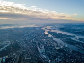 Aerial high flight over Kiev, haze over the city. Autumn morning, the Dnieper River is visible on the horizon.