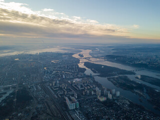 Aerial high flight over Kiev, haze over the city. Autumn morning, the Dnieper River is visible on the horizon.