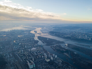 Aerial high flight over Kiev, haze over the city. Autumn morning, the Dnieper River is visible on the horizon.