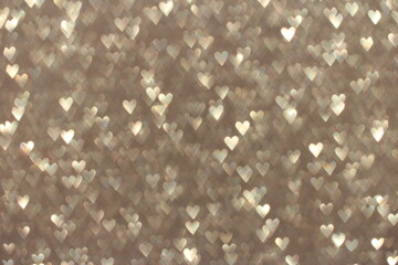 Beige background with shiny glitter and sequins in the shape of hearts.