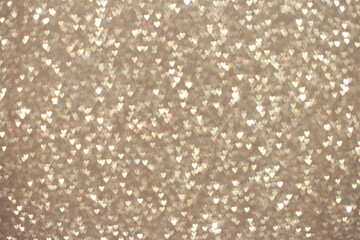 Beige background with shiny glitter and sequins. Textures hearts.