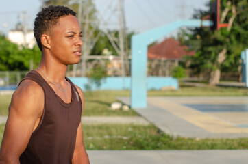 young dark-skinned latino man sitting on the stairs with a good body exercising in the park with...