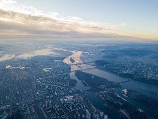 Aerial high flight over Kiev, haze over the city. Autumn morning, the Dnieper River is visible on...